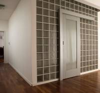 Családi ház belső tere üvegajtókkal és fa mintázatú padlóval.