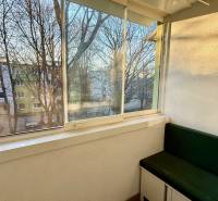 Üvegezett erkély egy 3 szobás lakásban zöld paddal és kilátással a fákra.