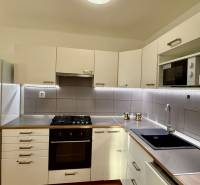 Konyha egy háromszobás lakásban fehér szekrényekkel és beépített készülékkel.