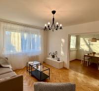 Nappali egy háromszobás lakásban fa dekoros padlóval és tágas ablakkal.