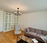 Nappali egy háromszobás lakásban, fa dekoros padlóval, világos bútorokkal és kanapéval.