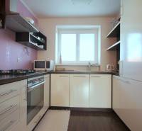 Konyha egy kétszobás lakásban gáz tűzhellyel és fa dekorációjú padlóval.