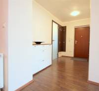 Előszoba egy kétszobás lakásban, fa mintázatú padlóval, fehér komóddal és függő akasztókkal.