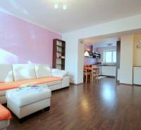 Nappali egy kétszobás lakásban sarokkanapéval és fa dekorációjú padlóval.