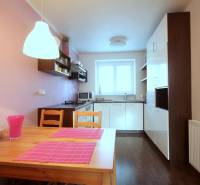 Kétszobás lakás konyhája fa dekoros padlóval és rózsaszín kiegészítőkkel.