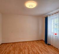 Szoba egy családi házban fa dekoros padlóval és függönyökkel az ablaknál.