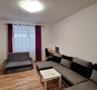 Nappali egy családi házban sarokkanapéval és fa mintázatú padlóval.