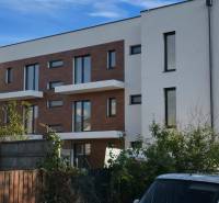 Fehér háromemeletes épület fa dekorációkkal a homlokzaton a Banka utcában, Pöstyénben.