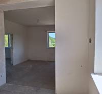 Családi ház belső tere befejezetlen falakkal és betonpadlóval.