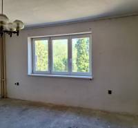 Szoba családi házban nagy ablakkal, eredeti csillárral és kilátással a zöldre.