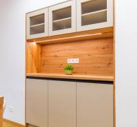 Konyhaszekrény felső szekrényekkel, fa dekorációval és növénnyel egy háromszobás lakásban.