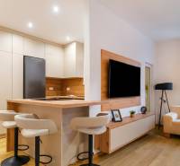 Konyha és nappali egy háromszobás lakásban fa dekoros padlóval, hangulatos ülőhelyekkel.