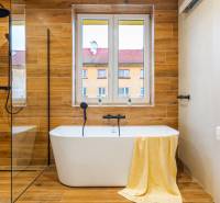 Fürdőszoba káddal, fa hatású padlóval egy háromszobás lakásban.