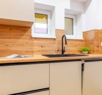 Konyha egy háromszobás lakásban fa dekorációval, mosogatóval és szekrényekkel.