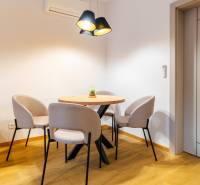 Háromszobás lakás elegáns étkezője kerek asztallal és székekkel, fa dekorációjú padlóval.