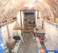 Családi ház alagsori pincéje téglaboltozattal és polcokkal, amelyeken befőttek vannak.