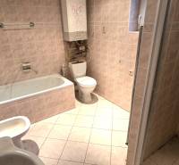 Fürdőszoba családi házban káddal, mosdóval és WC-vel. Világos színű csempék.