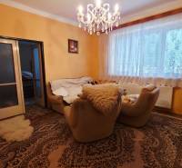 Nappali egy családi házban szőnyegekkel, csillárral és kényelmes fotelekkel.