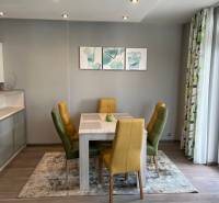 Étkező sarok egy 4 szobás lakásban színes székekkel és fa mintázatú padlóval.