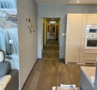 Nappali egy négy szobás lakásban, fa mintázatú padlóval és konyhabútorral.