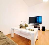 Nappali egy kétszobás lakásban, fa dekoros padlóval és fehér asztallal.