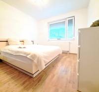 Hálószoba egy kétszobás lakásban fa mintázatú padlóval és nagy ággyal.