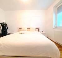 Hálószoba egy kétszobás lakásban ággyal, nyitott gardróbbal és fa dekoros padlóval.