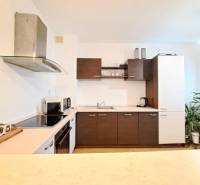 Konyha egy kétszobás lakásban fa szekrényekkel és konyhai eszközökkel a munkalapon.