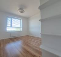 Szoba egy kétszobás lakásban fa dekoros padlóval, világos falakkal és ablakkal.