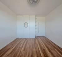 Szoba fa dekoros padlóval, beépített szekrénnyel és polcokkal egy kétszobás lakásban.