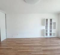 Szoba egy kétszobás lakásban, fa dekoros padlóval és fehér falakkal.