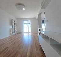 Nappali tér egy kétszobás lakásban, fa dekor padlóval és világos falakkal.