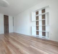 Nappali egy kétszobás lakásban, fa mintázatú padlóval és fehér falakkal.