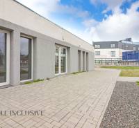 A Vajanského utcán, modern építészetű üzlethelyiségek mellett, szilárd burkolatú járdákkal.