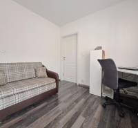 Kanapé és íróasztal egy családi házban, fa mintázatú padlóval.