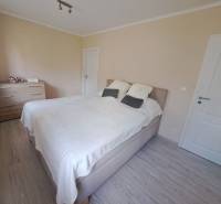 Hálószoba családi házban ággyal, komóddal és fa dekoros padlóval.