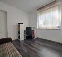 Szoba családi házban, fa dekorációs padlóval, asztallal, székkel és kanapéval.