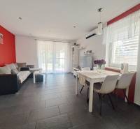 Nappali egy családi házban piros fallal, szürke csempével és fehér bútorokkal.