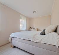 Világos hálószoba családi házban kényelmes ággyal és fa dekoros padlóval.