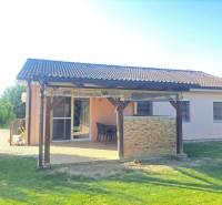 Családi ház Feketevárosban terasszal, kerttel és pergolával, zöld gyep veszi körül.