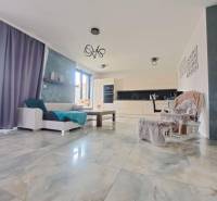 Nappali nagy ablakokkal és világos csempékkel egy családi házban.