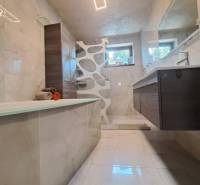 Fürdőszoba családi házban káddal, modern világítással, csempével és mosdóval.