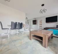 Családi ház belső tere világos csempékkel, modern bútorokkal és televíziós fallal.