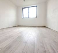 Családi ház szobája fa dekoros padlóval, fehér falakkal, egy ablakkal.