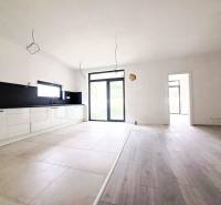 Tágas konyha egy családi házban, fa dekoros padlóval és nagy ablakokkal.