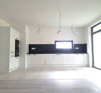 Konyha egy családi házban, fa dekor padlóval, fehér szekrényekkel és beépített készülékekkel.