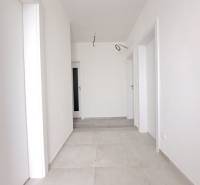 Világos folyosó egy családi házban, fehér falakkal és világos csempével.