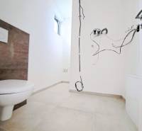 Egy családi ház fürdőszobája szabadon lévő kábelekkel és WC-vel, kiegészítők nélkül.