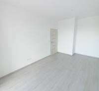 Szoba egy kétszobás lakásban fehér falakkal és fa dekorációjú padlóval.