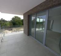 A galántai 2 szobás lakás erkélye csempével és üvegezéssel, zölddel körülvéve.